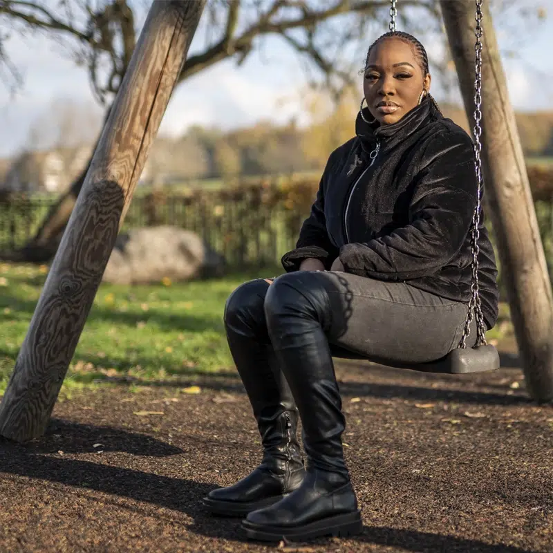 A woman sitting on a playground swing in a park