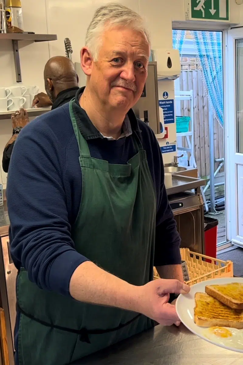 A male volunteer serving breakfast at the HARP day centre