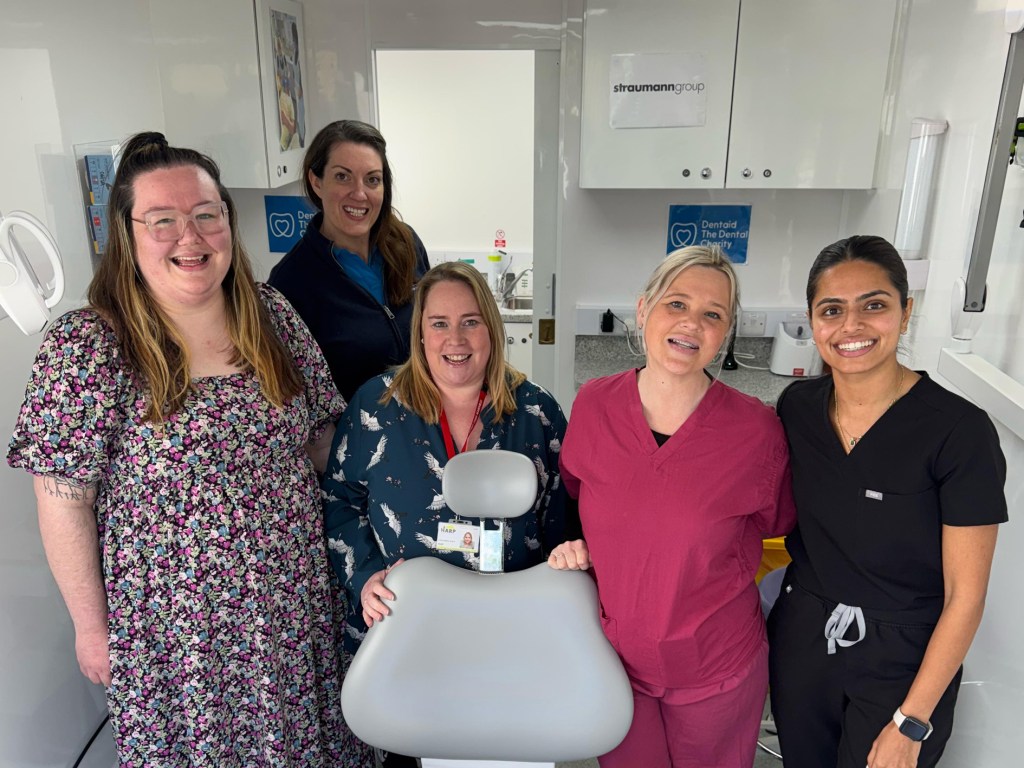 FIve women standing around a dentist chair in a mobile clinic